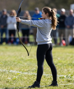 A young woman about to shoot an arrow from a bow.
